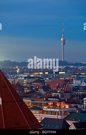 View towards the Olympiaturm (Olympic Tower) over the rooftops of buildings at sunset in the City of München (Munich) Bavaria, G Stock Photo