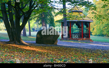 Wooden belvedere, big stone and pedestrian path in autumn city park Stock Photo