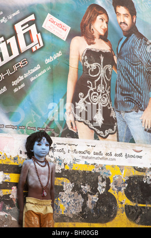Indian boy, face painted as the Hindu god Shiva standing in front of a Bollywood movie poster. Andhra Pradesh, India Stock Photo