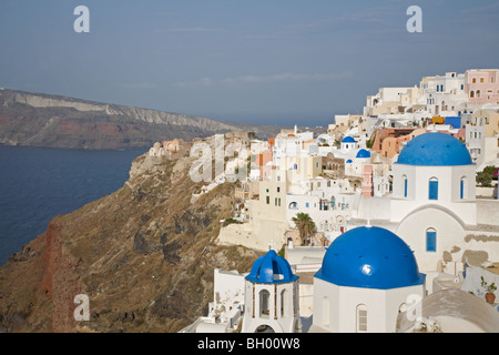 Oia town on clifftop with blue-domed white churches overlooking Santorini's caldera and lagoon water in the Mediterranean Sea Stock Photo