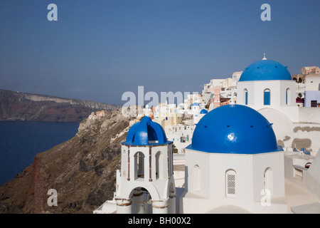 Picturesque clifftop town of Oia with three blue-domed white churches overlooking Santorini's caldera and lagoon in the Mediterranean Sea Stock Photo