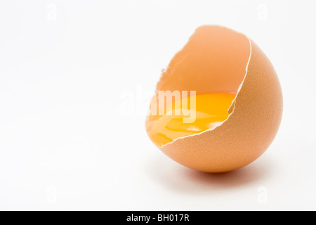 Single cracked open Hens Egg showing yolk isolated against white background Stock Photo