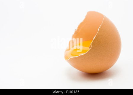 Single cracked open Hens Egg showing yolk isolated against white background Stock Photo