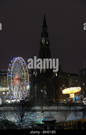 Scott Monument flanked by big Christmas Ferris Wheel and carousel in Princes Street Gardens, Edinburgh, Scotland, UK, at night Stock Photo