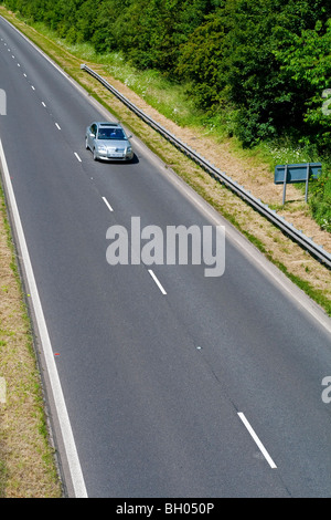 Car on two lane road with white lines in centre and crash barrier Stock Photo