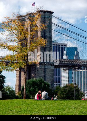 An Asian family picnics on the grass in Brooklyn Bridge Park, part of the DUMBO district in Brooklyn, NY beside Brooklyn Bridge Stock Photo