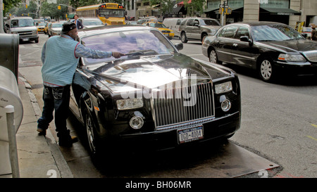 Parked outside the city's luxurious Hotel Carlyle, a luxurious Rolls-Royce auto gets dusted on New York City's Madison Avenue. Stock Photo