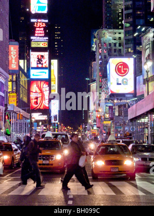 Traffic stops for pedestrians at night on Seventh Avenue in New York's Times Square with its bright outdoor signs. Stock Photo