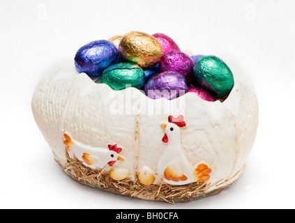 A small selection of colorful mini chocolate Easter eggs in a decorative egg ornament on a white background Stock Photo