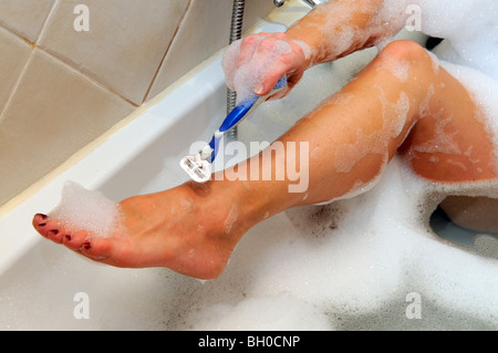 Woman using a Gillette safety razor to shave her legs Stock Photo