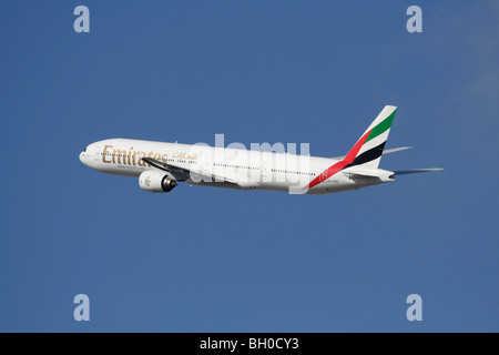 Emirates Boeing 777-300 long-haul passenger jet plane in flight against a blue sky Stock Photo