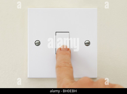 Finger on Light Switch turning off electricity Stock Photo