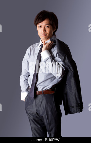 Successful Asian business man standing with confidence and jacket over his shoulder and hand in pocket, isolated. Stock Photo