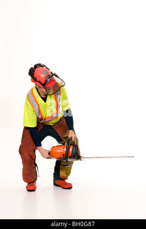 A lumberjack in full protective gear holds his chainsaw at an angle. Stock Photo