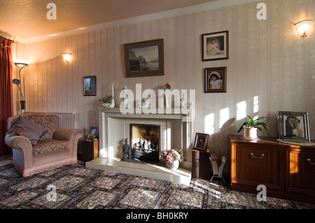 Horizontal wide angle interior of a traditional old-fashioned lounge with patterned carpet and large stone fireplace. Stock Photo