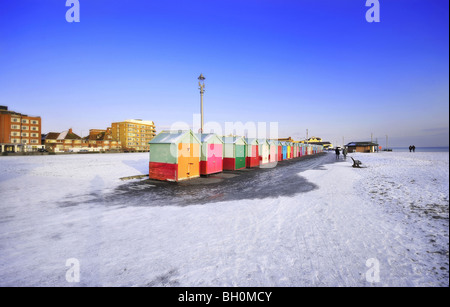 Snow on Brighton and Hove Beach with the colourful beach huts in the foreground Stock Photo