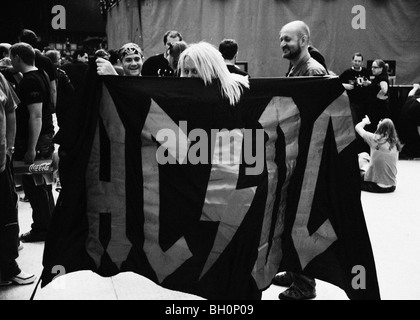 Female fan peering over AC/DC flag, Wembley Stadium, June 2009.  Mono image with light grain Stock Photo