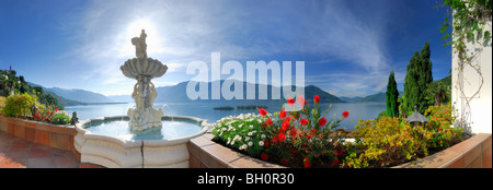 Panorama of lake Maggiore with isle of Brissago, Isole di Brissago, and Monte Gambarogno, fountain and flowers in the foreground Stock Photo