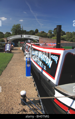 Traditional working narrowboat moored at Braunston Marina, looking towards the elegant cast iron bridge and the church spire Stock Photo
