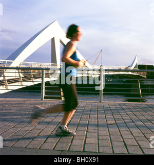 Young woman runner jogger on jog running jogging along the River Clyde past the Tradeston bridge in Glasgow Scotland UK Great Britain    KATHY DEWITT Stock Photo