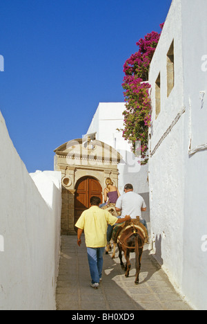 Man and woman riding donkeys along an alley, Lindos, Island of Rhodes, Greece, Europe Stock Photo