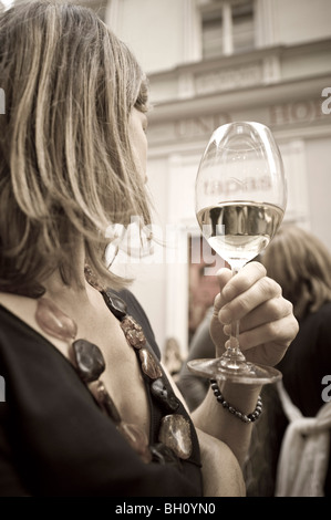 Blond woman holding a wine glass turning away, Linz, Upper Austria, Austria Stock Photo