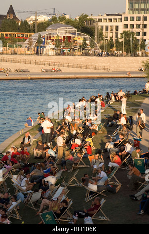 People sitting on deck chairs at the bank of the river Spree in the sunlight, Berlin, Germany, Europe Stock Photo