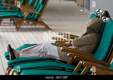 Woman wrapped against the breeze on the QM2 cruise ship Stock Photo