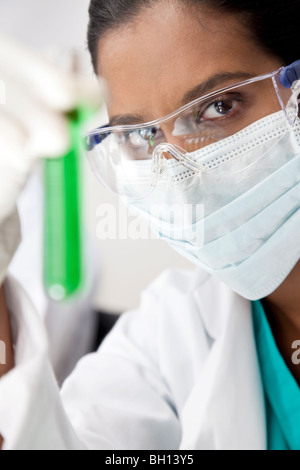 A female Asian medical or scientific researcher or doctor looking at a test tube of a green solution in a laboratory. Stock Photo