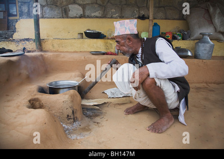 Elderly man stoking a wood fire, Pokhara, Nepal Stock Photo