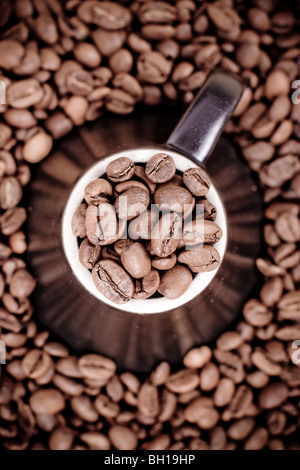 Coffee beans placed on top of a brown coffee mug or cup with a white outline. Stock Photo