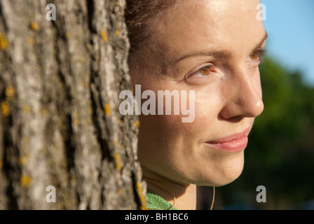 Head shot of woman in her 40s beside tree, Assiniboine Park, Winnipeg, Manitoba, Canada Stock Photo