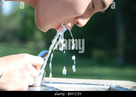 Asian man drinking from water fountain in Assiniboine Park, Winnipeg, Manitoba, Canada Stock Photo