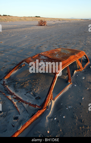 Rusted car wreck buried in sand. Waitarere Beach, Horowhenua, Wellington, New Zealand Stock Photo