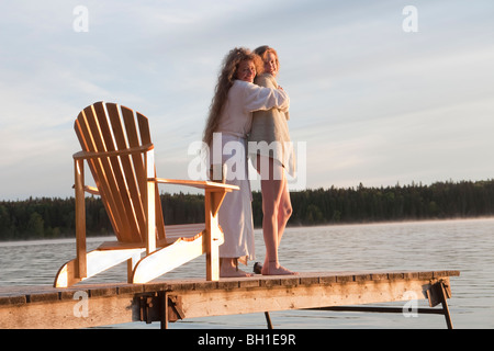 Two women embrace on dock, Clear Lake, Manitoba, Canada Stock Photo