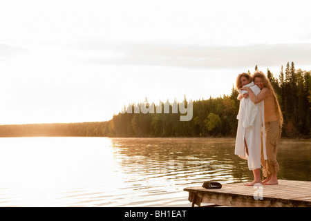 Two women embrace on dock, Clear Lake, Manitoba, Canada Stock Photo