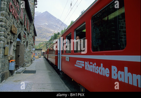 Woman smiling out of window of red train of Rhaetische Bahn at station Alpe Gruem, Alp Gruem, Ferrovia Raetia, Bernina range, Be Stock Photo