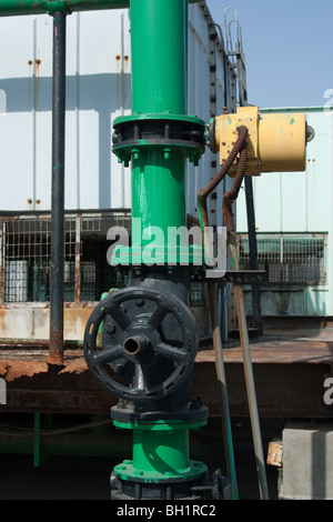 A valve used as part of an industrial water cooling tower. The valve controls the flow of water. In the background, mesh visible Stock Photo