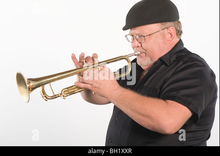Mature man in flat cap playing the trumpet Stock Photo