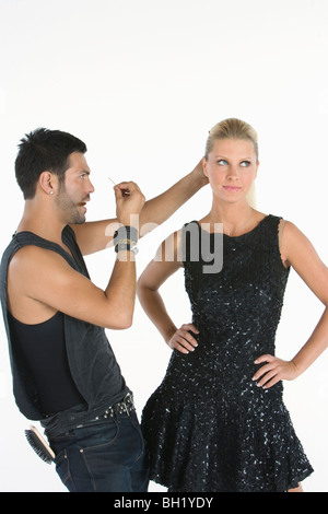 Hair stylist makes adjustments to model standing with hands on hips Stock Photo