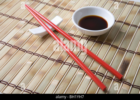 Red chopsticks and side bowl of soy sauce Stock Photo