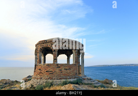 Rocky summer coastline and cape with pavilion on blue sky background Stock Photo