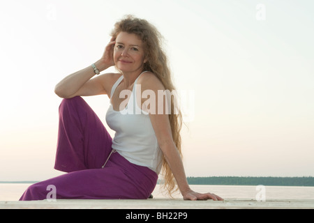 Woman seated on dock by Clear Lake, Manitoba, Canada Stock Photo