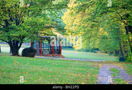 Wooden belvedere, big stone and pedestrian path in autumn city park Stock Photo