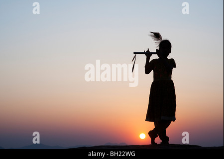 Silhouette of an Indian girl pretending to be Lord krishna at sunset. Andhra Pradesh, India Stock Photo