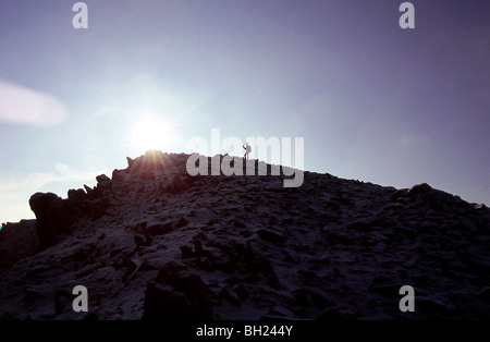 Mountaineer reaching the peak on a sunny day Stock Photo