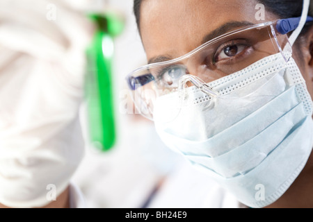 Environmental concept shot of female Asian medical or scientific researcher or doctor looking at a test tube of a green solution Stock Photo