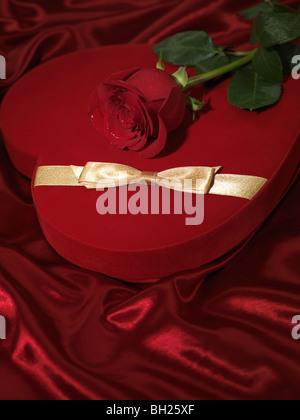 Red heart-shaped gift box and a red rose Stock Photo