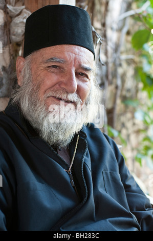 Older Greek Orthodox priest smiling with beard and robes Stock Photo