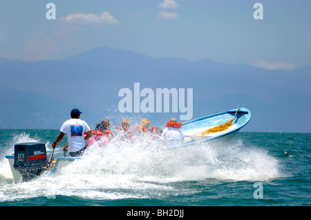 Small john boat loaded with tourist races on the Pacific ocean as it splashes through the deep blue water of the tropics. Stock Photo